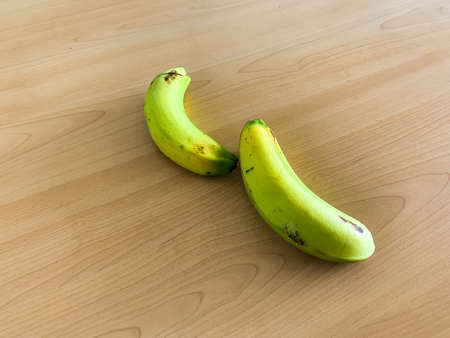 light green bananas on a wooden tableの写真素材