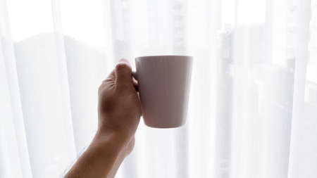 a hand holding a white glass