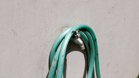 a water hose that is rolled up on a water faucetの写真素材