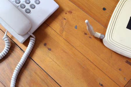 closeup of a wireless router and telephone on wooden table
