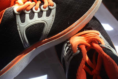 Close up of running shoes with orange and black shoelaces.