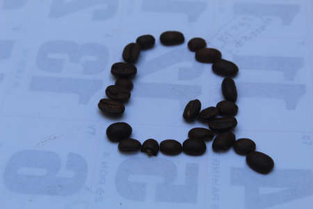 Coffee beans in the shape of the letter Q on a blue background.