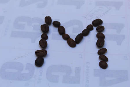 Coffee beans in the form of a letter M on the background of the calendar