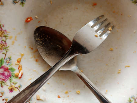 Spoon and fork on a white plate. Close-up.の写真素材