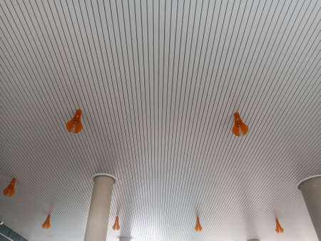 The ceiling of the building is covered with a white line with orange lamps.の写真素材