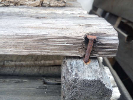 Rusty nail on a piece of wood in the background of old boardsの写真素材