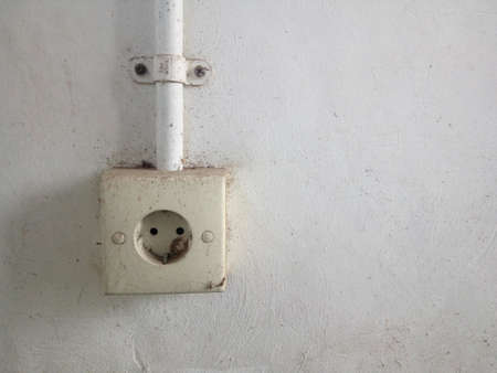 Old power socket on a white concrete wall. Close up view.の写真素材