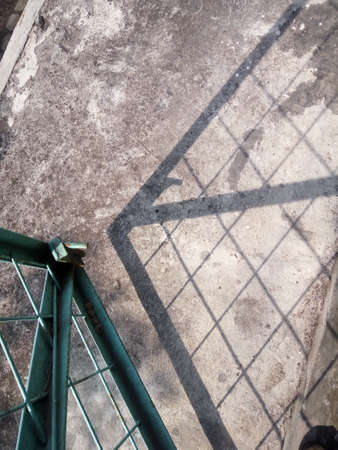 A view of the shadow of a steel fence on the ground.の写真素材