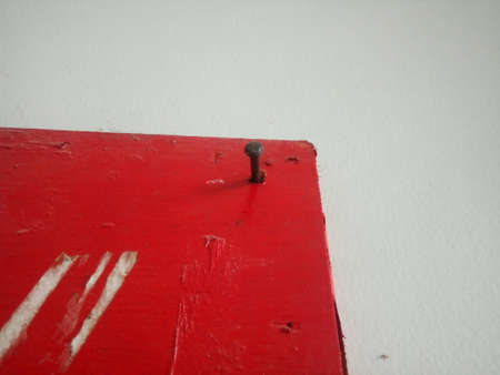 A closeup shot of a metal nail on a red painted wallの写真素材