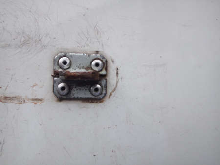 Close up of old metal door hinge on a white wall background.の写真素材