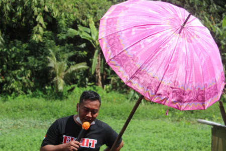 Asian man,  wearing black t-shirt,  holding pink umbrella,  in  garden,  at   UDONTHANI province...