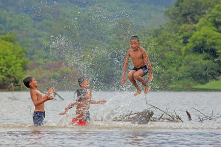 Village's kids jump and play splashing water in the riverのeditorial素材