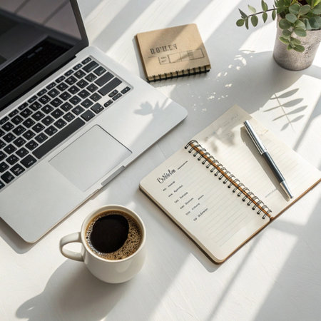 Notebook with pen, coffee cup and laptop on white table.の素材