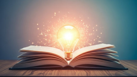 Open book with glowing light bulb on wooden table. Knowledge and education conceptの素材