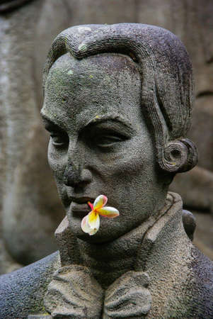 Stone sculpture head with real flower in mouthの写真素材