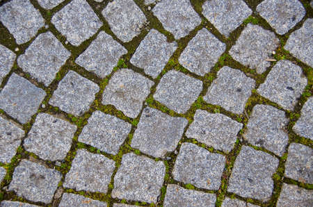 Fragment of a cobbled gray cobblestone pavement for use as an abstract background and texture.
