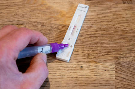 Bamberg, Germany - 8.4.2021. Antigen Test Sample being dropped by hand onto Device of the manufacturer Hotgen.のeditorial素材