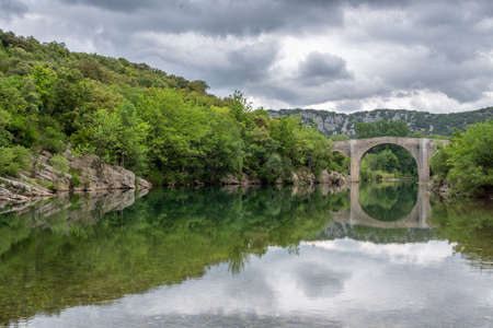 View of the river Herault in the South of France with the bridge of Saint Etienne dIssensac in the backgroundの写真素材