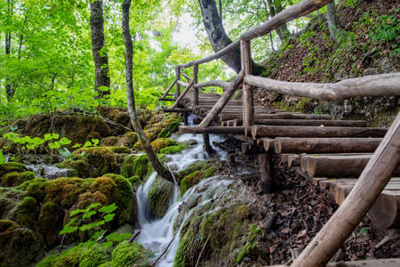 Plitvice National Park, Croatia - 17.8.2021. Popular touristic wooden bridge in the deep summer forest. Wooden promenade with clean brook and spectacular waterfalls.のeditorial素材