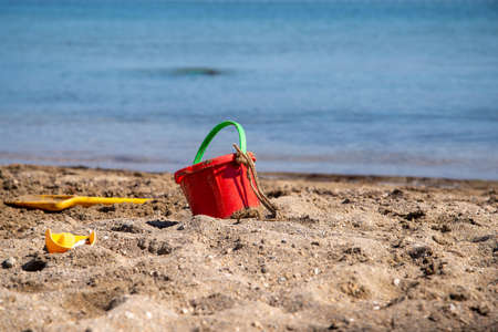 Sand toys on the beach with water surface in the backgroundの写真素材