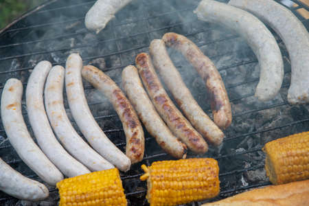 View from the top of a smoking grill with sausages and corn on the cob