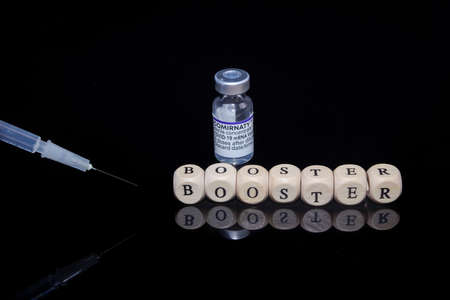 Bamberg, Germany - 16.11.2021. Letter cubes form the word booster, BioNTech-Pfizer Comirnaty original vial and syringeのeditorial素材