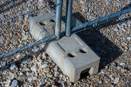 A solid concrete block that has holes in it is firmly attached to a fenceの写真素材