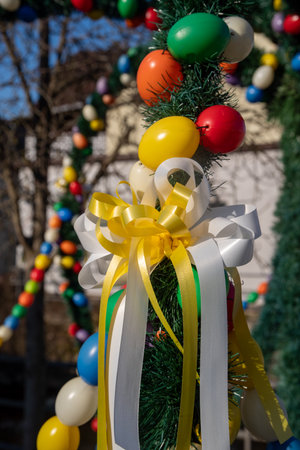 Colorful Easter decorations are displayed on a pole with a yellow bow
