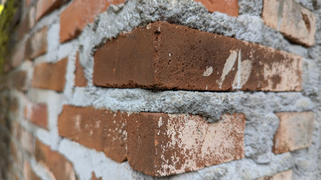 A close-up shot captures the intricate details of a weathered red brick wall, showcasing the rough...
