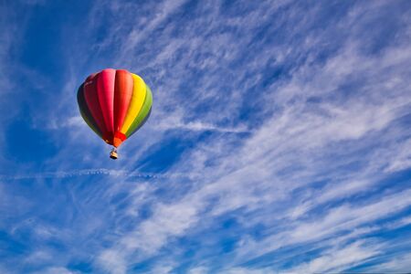 Hot air balloon flying alone in the blue sky with clouds, multicolored, rainbow.の写真素材
