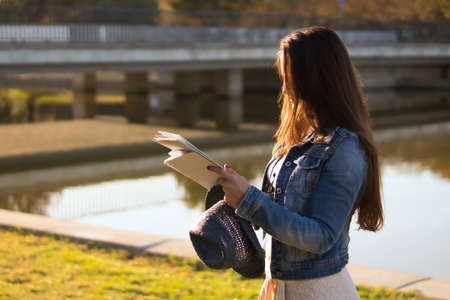 Young woman with blue hat and denim jacket consulting a map during a trip outside with an unfocused background.の写真素材