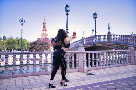 Multi-ethnic young couple doing figures while dancing bachata sensually outdoors.の写真素材