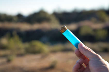 Blue shotgun cartridge already fired, held by one hand and picked up from the field. Concept hunting, ammunition, private preserve, garbage.の写真素材