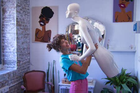 Young woman, designer, dressmaker and artist, dancing with a female mannequin inside her studio. Concept fashion, design, mannequin, modern.の写真素材