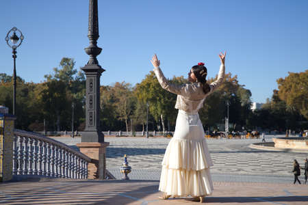 Young flamenco woman, Hispanic and brunette, in typical flamenco dance suit, with bullfighter jacket, dancing with arms up. Concept of flamenco, dancer, typical Spanish dance.の写真素材