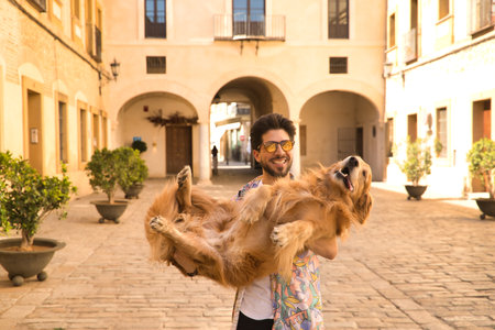 Young Hispanic man with beard, sunglasses and white shirt, leaning out with his dog leaning on a railing in funny attitude. Concept animals, dogs, love, pets, golden.の写真素材