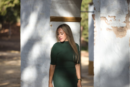 Young, beautiful, blonde woman with green eyes, wearing a green dress, leaning on a white bow between lights and shadows, with a sad and worried look. Concept beauty, fashion, trend, eyes, sadness.の写真素材