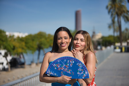 Two young, beautiful and South American women, brunette and blonde posing in a funny attitude with a fan during their holidays in Spain. Concept beauty, fashion, couples, travel.の写真素材