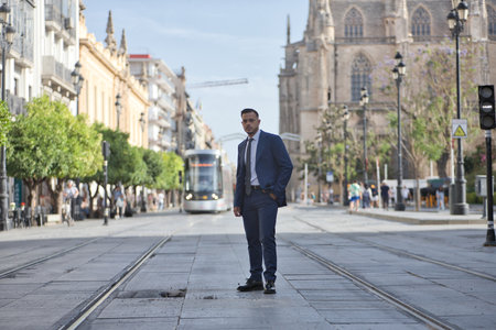 Young, brunette, Hispanic, modern executive in suit and tie, posing with one hand in his pocket in the middle of an avenue in the city of Seville. Concept business, company, leader.の写真素材