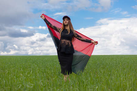 young beautiful ukrainian girl with an excellent figure in a black short dress holds a national Ukrainian red black flagの写真素材