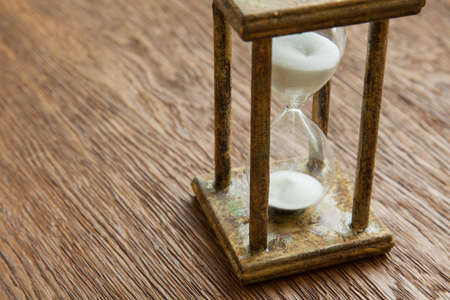 Hourglass on the Oak table as time passing concept for business deadline, urgency and running out of time.の写真素材