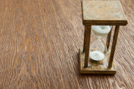 Hourglass on the Oak table as time passing concept for business deadline, urgency and running out of time.の写真素材