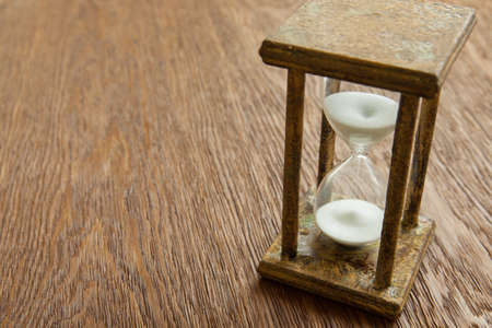 Hourglass on the Oak table as time passing concept for business deadline, urgency and running out of time.の写真素材