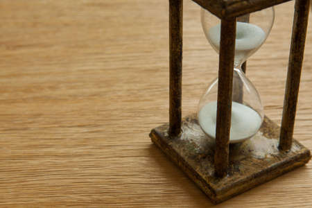 Hourglass on the Oak table as time passing concept for business deadline, urgency and running out of time.の写真素材