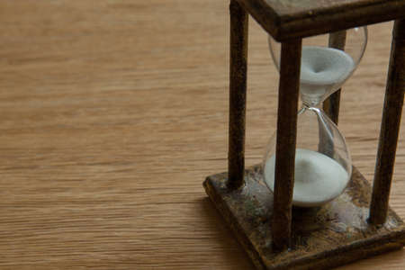 Hourglass on the Oak table as time passing concept for business deadline, urgency and running out of time.の写真素材