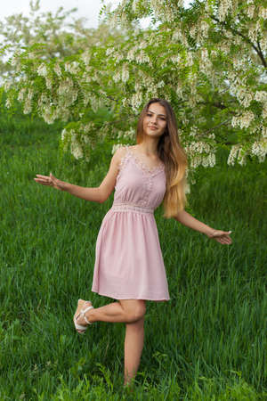 sexy girl with long hair and slender figure standing in green garden in springの写真素材
