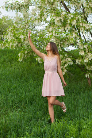 sexy girl with long hair and slender figure standing in green garden in springの写真素材