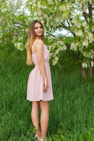 sexy girl with long hair and slender figure standing in green garden in springの写真素材