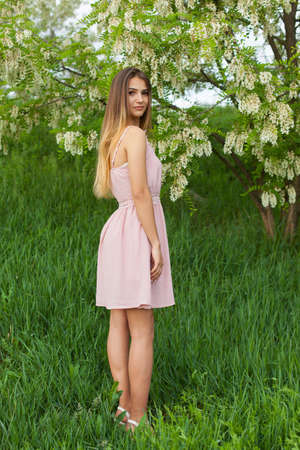 sexy girl with long hair and slender figure standing in green garden in springの写真素材