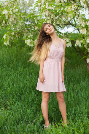sexual girl has dissolved long hair sunny in the afternoon opposite blossoming white acaciaの写真素材